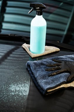 Profesyonel araba valeliği. Arabanın yüzeyini temiz ve parlak yapmak için hızlı bir temizleyici spreyi sıktıktan sonra araç silme işlemi. Araba gövdesini mikro fiber bez kullanarak cilalamak