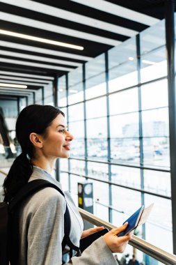Havaalanı terminalinde akıllı telefonunu kullanarak uçuş numarasını kontrol eden bir kız. Seyahat ve tatil kavramı