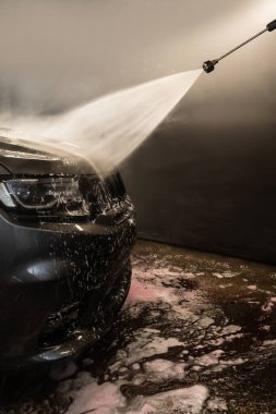Aracın yüzeyindeki köpüğü yıkıyorum. Araba yıkama servisinde yüksek basınçlı su jeti ile cesedi temizlemek.