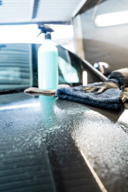 Profesyonel araba valeliği. Arabanın yüzeyini temiz ve parlak yapmak için hızlı bir temizleyici spreyi sıktıktan sonra araç silme işlemi. Araba gövdesini mikro fiber bez kullanarak cilalamak