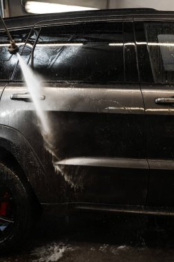 Yüksek basınçlı çamaşır makinesiyle müşterilerin arabasını yıkamak. Köpüğü durulamak için arabaya su dökerek. self-servis araba yıkama