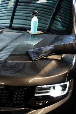 Polishing car body with microfiber rag. Wiping car surface with cloth after carwash. Professional car detailing clipart