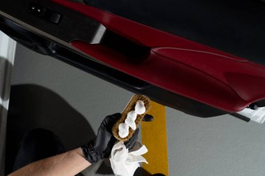 Otomobil kapısındaki toz ve kiri temizleme işlemi. Araba temizleyicisi otomatik kapıyı fırça ve deterjanla temizliyor.