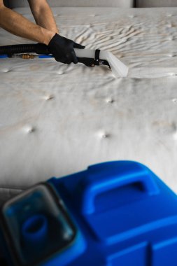 Temizlikçi yatak odasındaki yatağı temizlemek için sökücü kullanıyor. Koltuktaki lekeleri çıkarmak için çıkarıcıyla temizliyorum. Evin düzenini sağlamak için kanepeyi sökücü makineyle temizliyorum.