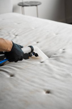Koltuktaki lekeleri çıkarmak için çıkarıcıyla temizliyorum. Evin düzenini sağlamak için kanepeyi sökücü makineyle temizliyorum. Temizlikçi yatak odasındaki yatağı temizlemek için sökücü kullanıyor.