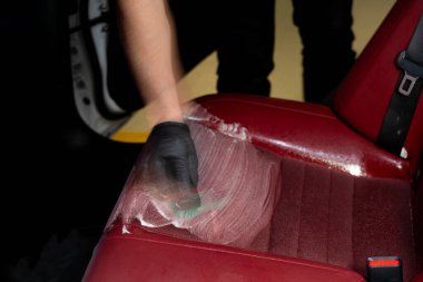 Araba koltuğunu deterjanla fırçalamak. Daha önce temizlik spreyinin sıçrattığı el fırçaları kırmızı oto koltukları. Araba koltukları fırça ve temizleme işlemiyle detaylandırılıyor