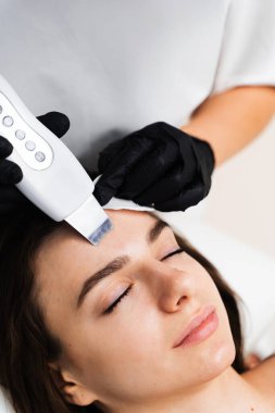 Kabuk soyma donanımı uygulanıyor. Ultrason kozmetoloji cihazı yardımıyla yüz derisi temizleniyor