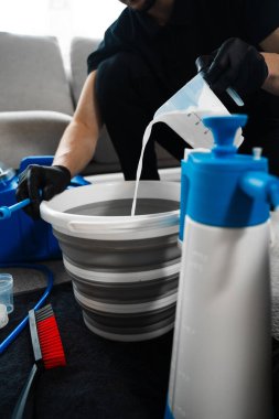 Oturma odasındaki mobilyaları temizlemek için kovaya oksijen suyu karışımı döküyorum. Lekeleri çıkarmak ve beyaz mobilyaları oksijenli suyla parlatmak.