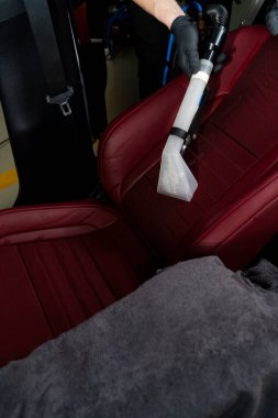 Özel elektrikli süpürge başlığıyla oto koltukları detaylandırılıyor. Elektrikli süpürgeyle arka koltuğu süpürüyor.