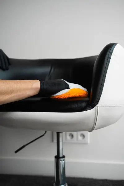 stock image Cleaning dark leather chair with a soft brush and detergent. Dealing with stains and dust on leather furniture using brush and foam