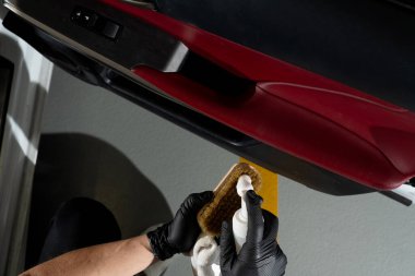 Otomobil kapısındaki toz ve kiri temizleme işlemi. Araba temizleyicisi otomatik kapıyı fırça ve deterjanla temizliyor.