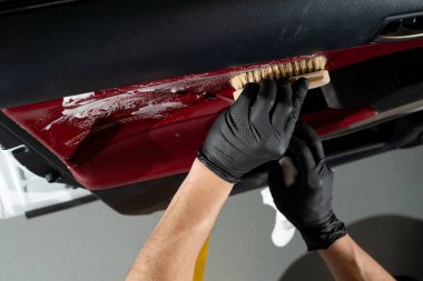 Arabanın kapı panelini deterjanla temizleme işlemi. Sabunlu bir fırçayla arabanın kapısını temizleyen siyah bir eldiven verin. Ayrıntılı işlem