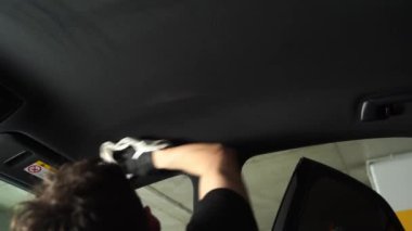 4K video kapak arabasının detaylarını gösteriyor. Arabadaki ana başlığa deterjan sıkıyorum. El, arabanın tavanını deterjan ve mikrofiber halıyla temizliyor.