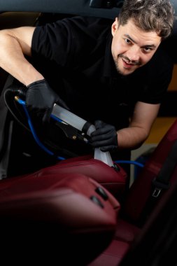 Özel vakumlu hortumla arka koltuğu temizliyorum. Elektrikli süpürge yardımıyla araç koltukları ayrıntılandırılıyor