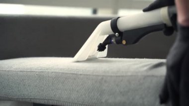 Döşeme mobilyalarını toz ve lekelerden temizlemek için sökücü kullanıyor. Temizleyici, deterjan 4k video ekstraktör kullanan kuru temizleme koltuğu.