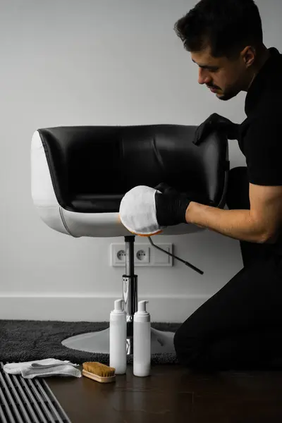 stock image Dealing with stains and dust on leather furniture using brush and foam. Cleaning dark leather chair with a soft brush and detergent