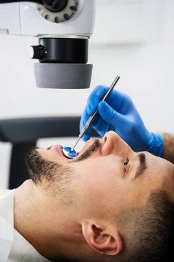 Diş hekimi dijital mikroskobu çalışıyor. Dişçi hastanın dişlerini parlatmak için ameliyat mikroskobu kullanıyor.
