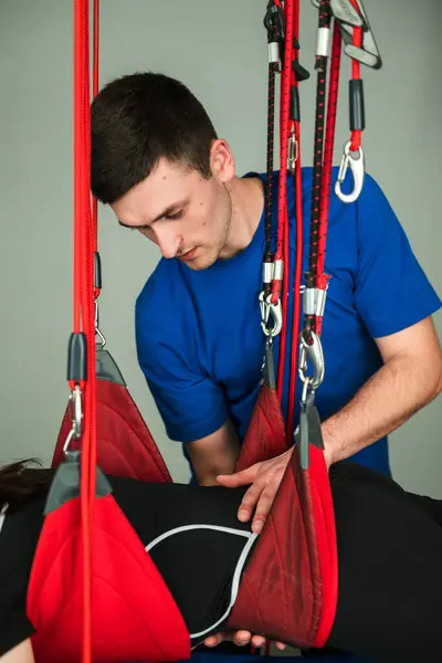 stock image Medical Red Cord physiotherapies to recover from muscle pain. Girl is hanging on red cord at rehabilitation center. Supervised help in injury treatment with red rope exercises