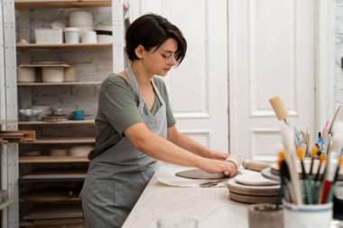 Yuvarlanan ahşap sopa düz bir kil yaprak yapmak için. Kili kesip monte etmek için hazırlıyorum. Seramik işçiliğinde Slap geliştirme yöntemi