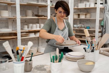 Keskin bir çömlek bıçağı kullanarak kilden mükemmel yuvarlak bir şekil çıkarmışlar. Seramik dersi. Çamuru yuvarlak bir forma modellemek