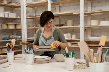 Seramik atölyesi. Kil ürünlerine daha fazla nem uygulamak. Süngerle kil yumuşatmak. Çömlekçilik dersi için sünger kullanıyorum. Aşırı nemden kurtulmak için sünger emiyor.