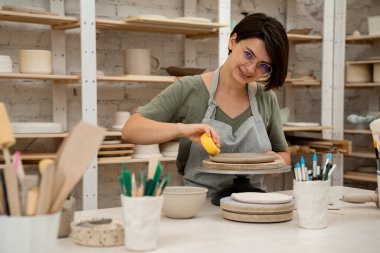 Seramik atölyesi. Kil ürünlerine daha fazla nem uygulamak. Süngerle kil yumuşatmak. Çömlekçilik dersi için sünger kullanıyorum. Aşırı nemden kurtulmak için sünger emiyor.