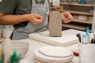 Büyük bir bloktan kil kesmek için kablo kesicisi. Çömlek ürünü oluşturmadan önce gerekli olan kilden bir parça kesmek. Seramik atölyesinde kil kesmeyi öğreniyorum.
