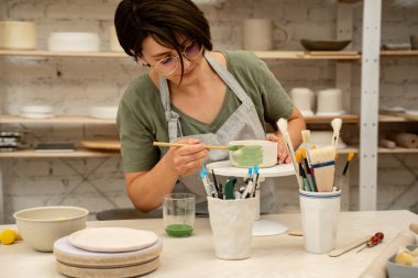 Akrilik boya ve fırça kullanarak seramik ürünler boyamak. Boya ve suyla kil bir projenin renkli bir dekorasyonunu yapmak