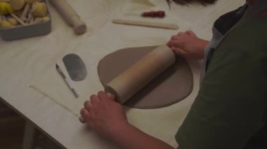 Kız kil 4K 'lık bir video yapmak için tahta sopa kullanıyor. Kili kesip monte etmek için hazırlıyorum. Seramik işçiliğinde Slap geliştirme yöntemi