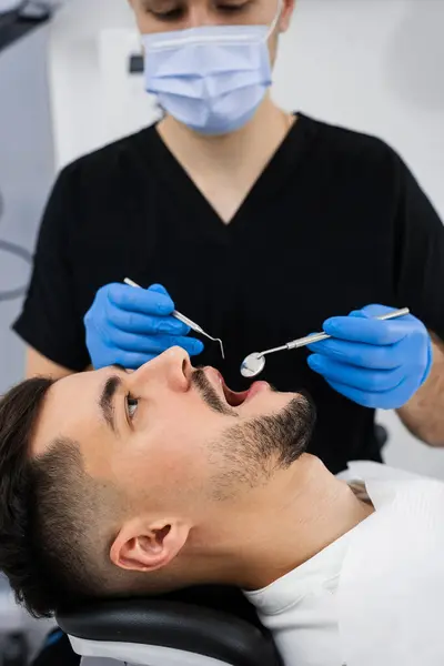 stock image Preventative dental checkup closeup. Dentist uses dental explorer and mirror to advise the patient