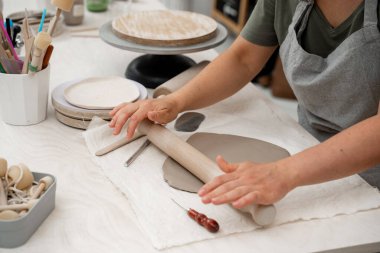 Kili kesip monte etmek için hazırlıyorum. Seramik işçiliğinde Slab inşa yöntemi. Düz bir kil tabaka oluşturmak için tahta bir sopa kullanıyor.