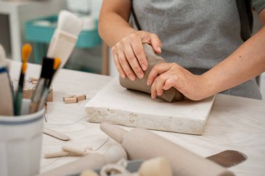 Uygun bir tutarlılık yaratmak için çömlek projesine başlamadan önce killeri sıkıştırmak. Seramik bir ürünün bozulmasını önlemek için modellemeden önce kilden hava kabarcıkları kaldırılıyor