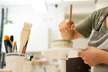 Akrilik boya ve fırça kullanarak seramik ürünler boyamak. Boya ve suyla kil bir projenin renkli bir dekorasyonunu yapmak