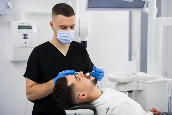 stock image Dentist uses dental explorer and mirror to advise the patient. Preventative dental checkup closeup