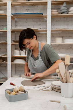 Seramik işçiliğinde Slab inşa yöntemi. Düz bir kil örtmek için tahta bir sopa kullanıyor. Kil kesim ve montajı için hazırlanıyor