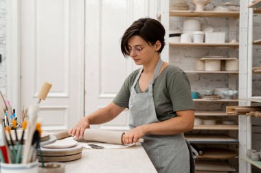 Seramik işçiliğinde Slab inşa yöntemi. Düz bir kil örtmek için tahta bir sopa kullanıyor. Kil kesim ve montajı için hazırlanıyor