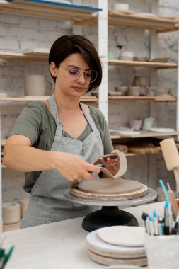 Keskin bir çömlek bıçağı kullanarak kilden mükemmel yuvarlak bir şekil çıkarmışlar. Seramik dersi. Çamuru yuvarlak bir forma modellemek