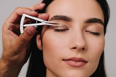 Üst blefaroplasti. Plastik cerrah, Castroviejo kalibresini kullanarak hastasının gözünün içindeki cerrahi mesafeyi ölçüyor. Göz kapaklarını düzeltmek için biofaroplasti hazırlanıyor.