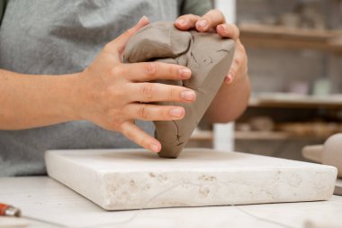 Uygun bir tutarlılık yaratmak için çömlek projesine başlamadan önce killeri sıkıştırmak. Seramik bir ürünün bozulmasını önlemek için modellemeden önce kilden hava kabarcıkları kaldırılıyor