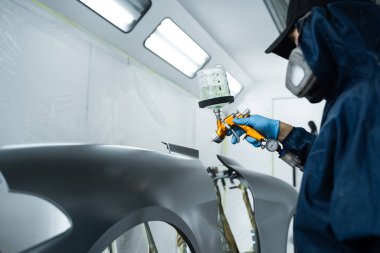 Araba boyacısı LVLP sprey tabanca kullanarak arabaya lakquer uyguluyor. Yüzeye pürüzsüz bir görünüm vermek için metalin üzerine lakquer yerleştiriliyor