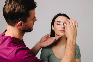 Üst blefaroplasti. Plastik cerrah, Castroviejo kalibresini kullanarak hastasının gözünün içindeki cerrahi mesafeyi ölçüyor. Göz kapaklarını düzeltmek için tıbbi prosedür hazırlanıyor.