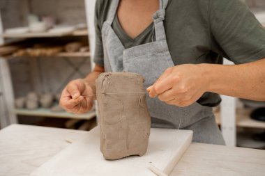 Çömlek ürünü oluşturmadan önce gerekli olan kilden bir parça kesmek. Seramik atölyesinde kil kesmeyi öğreniyorum. Büyük bir bloktan kil kesmek için tel kesici.