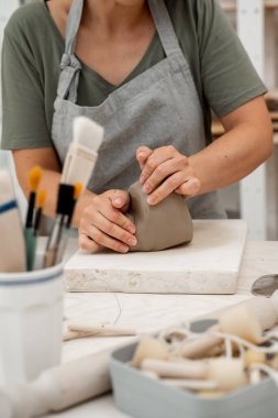 Uygun bir tutarlılık yaratmak için çömlek projesine başlamadan önce killeri sıkıştırmak. Seramik bir ürünün bozulmasını önlemek için modellemeden önce kilden hava kabarcıkları kaldırılıyor