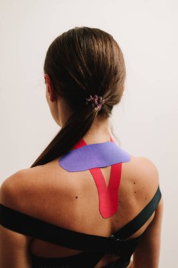 Spor sakatlığı sonrası kas uyarımını geliştirmek için kineziyoloji bandıyla sırt bandı. Genç kız şişliği azaltmak için esnek bantlarla rehabilitasyona gidiyor.