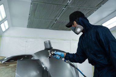 Araba boyacısı aracın rengini sünger ve boya spreyi kullanarak değiştiriyor. İşçi arabayı HVLP sprey tabancasıyla koyu renklere boyuyor.