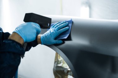 Tamirci, metali boyaya hazırlamak için statik tabancayla çalışıyor. Hasarları önlemek için anti statik silah kullanmak ve arabayı boyayla kaplamadan önce tozu silmek.