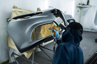 Araba boyacısı LVLP sprey tabanca kullanarak arabaya lakquer uyguluyor. Yüzeye pürüzsüz bir görünüm vermek için metalin üzerine lakquer yerleştiriliyor