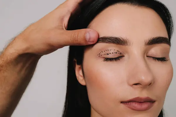 Blefaroplasti işaretleniyor. Doktor üst göz kapağı ameliyatı için tıbbi işaretle bir plan hazırlıyor. Göz kapaklarını kusursuz bir planla kaldırıyorum.