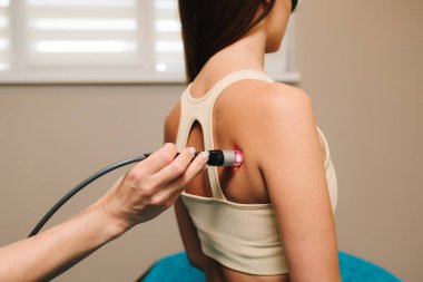 Kronik sırt ağrısı için lazer tedavisi. Hasarlı kas dokularını ve sinirleri onarmak için etkili bir lazer terapisi. Kadın acı, iltihap ve sırt ödemini azaltmak için kırmızı ışıkta iyileşiyor.