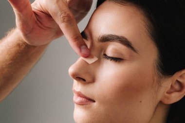 Burun estetiği. Şeklini korumak için burun üstüne bandaj uygulamak, şişliği azaltmak ve görünümü iyileştirmek. Estetik cerrah burun üstüne burun bandı takıyor.